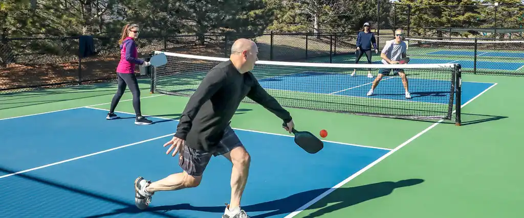 Mid-age pickleball players engaged in a doubles match, showcasing fun and camaraderie on a well-maintained outdoor court